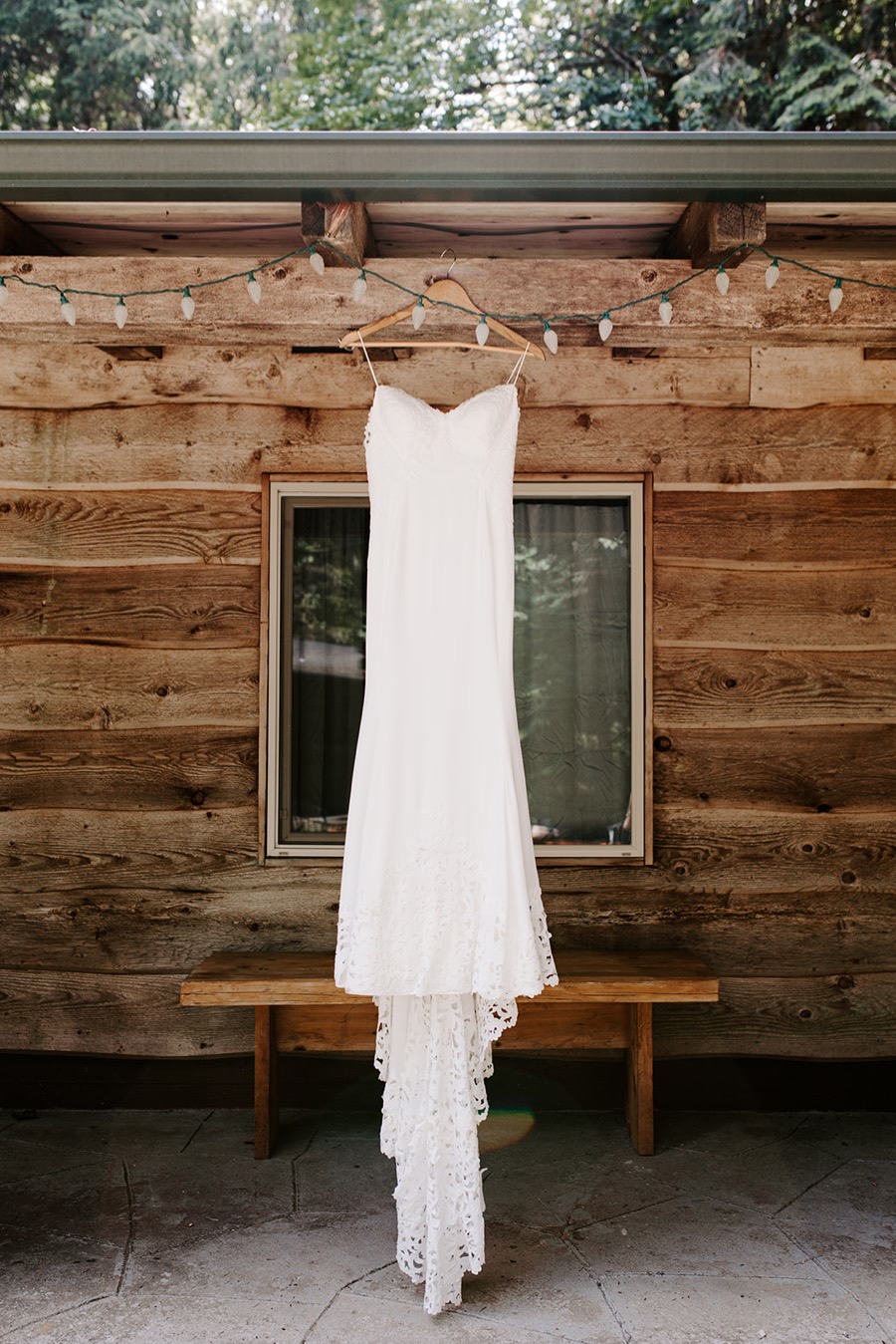 wedding dress hanging from wood log cabin in woods