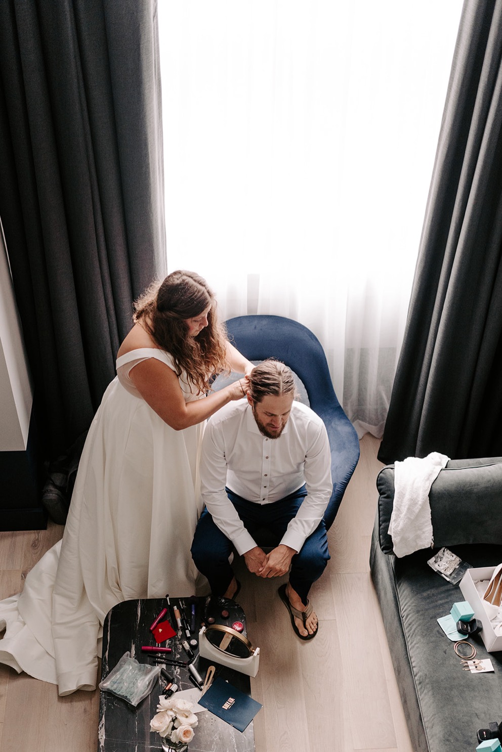 bride and groom getting dressed in light filled hotel room