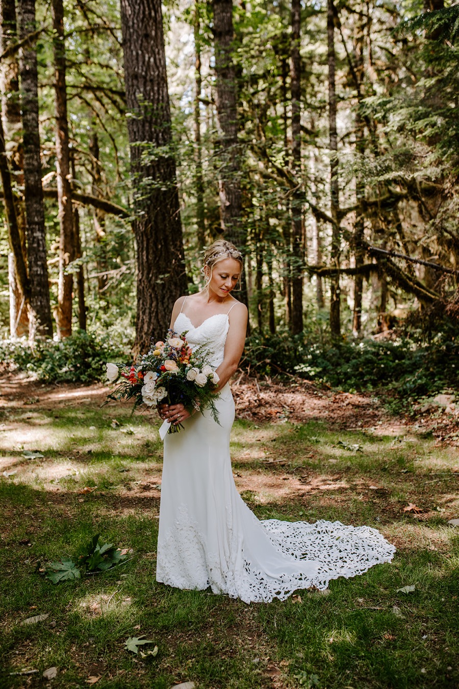 bride holding bouquet in middle of forest