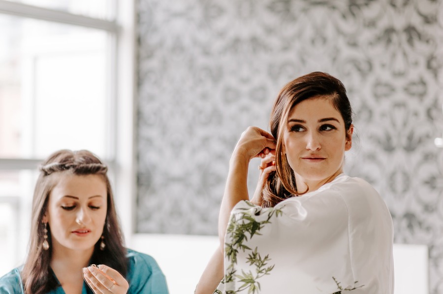 bride and maid of honour fixing hair and makeup