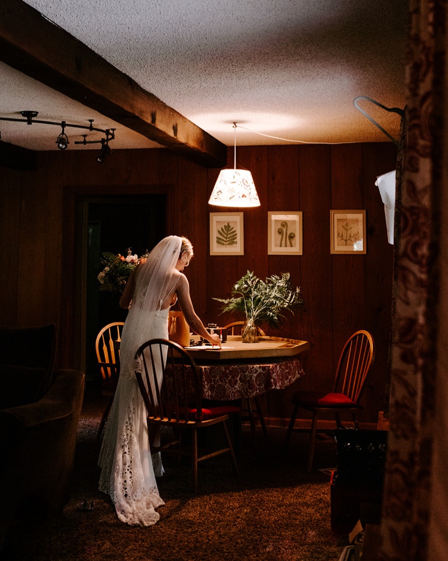bride standing over wooden table in dimly lit cabin