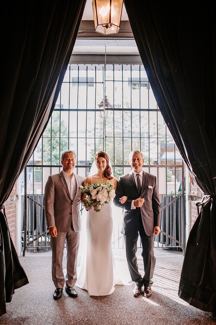 bride standing with two men in suits