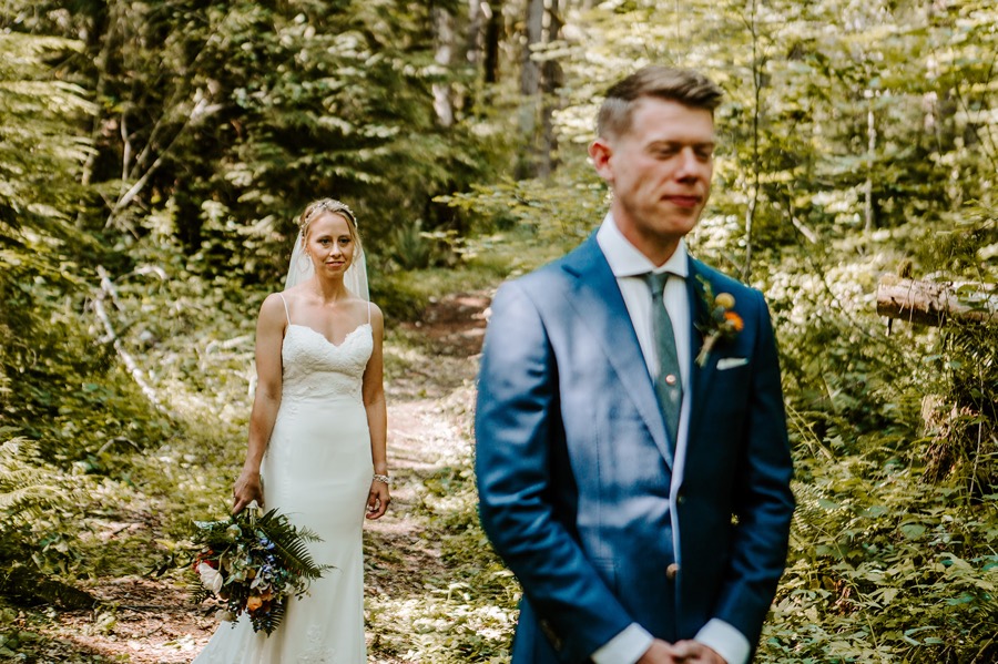 bride walking toward groom in forest
