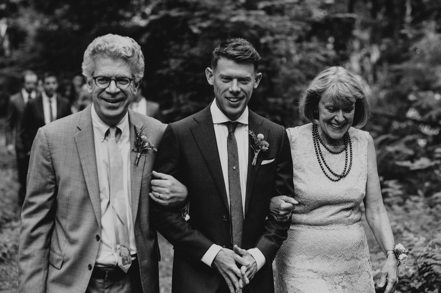 groom walking down aisle with parents on either arm