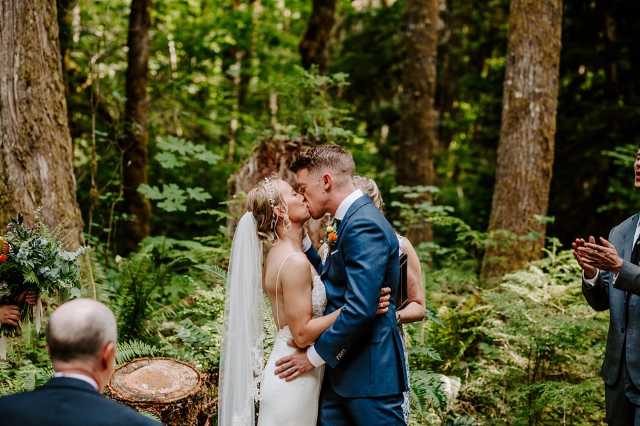 bride and groom first kiss during outdoor forest wedding