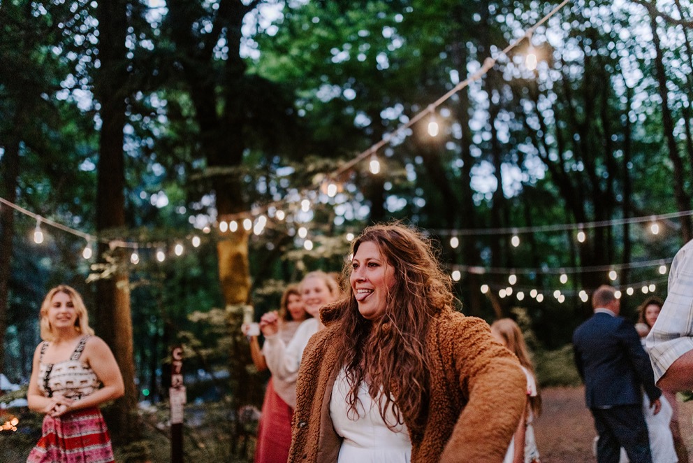 bride dances under patio lights during forest wedding reception