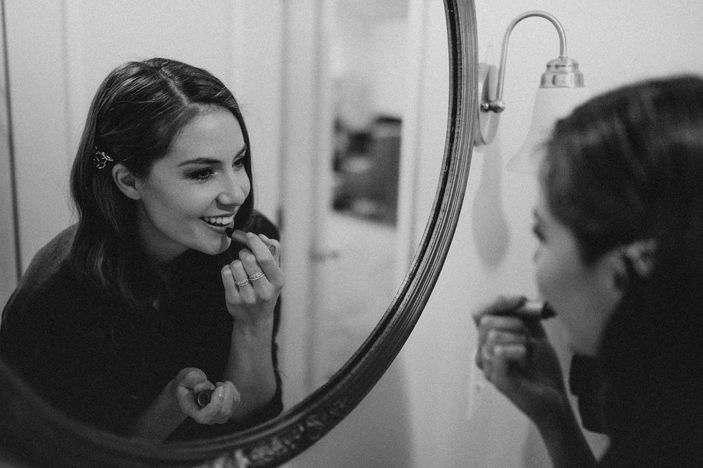 bride puts on her lipstick while getting ready for her elopement day
