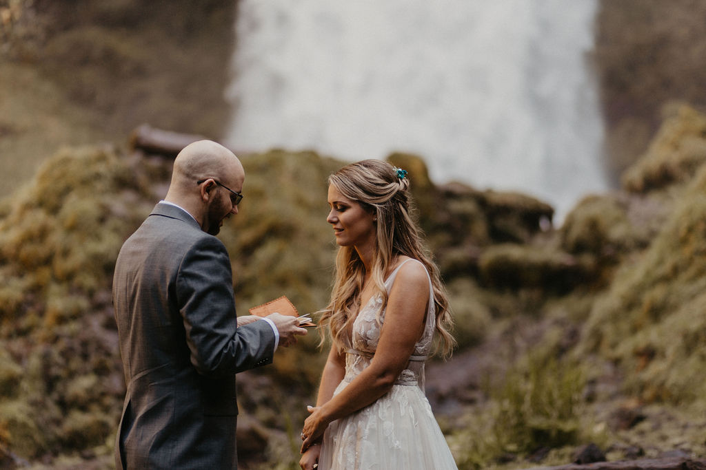 Bride and groom share vows at an elopement ceremony in front of a waterfall in Oregon