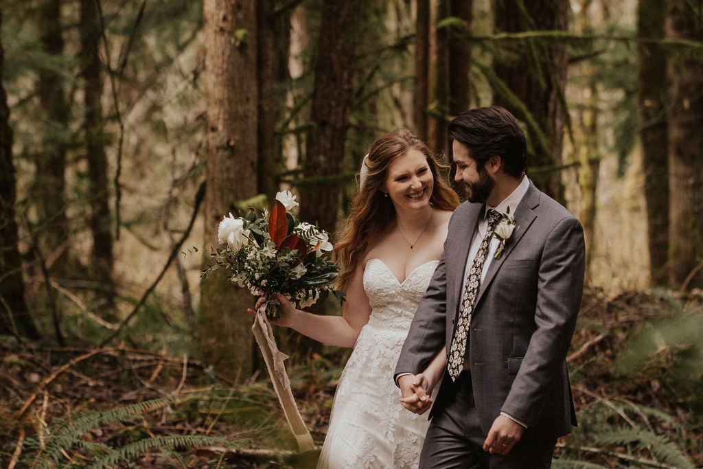 bride and groom hike through the forest at their washington adventure elopement