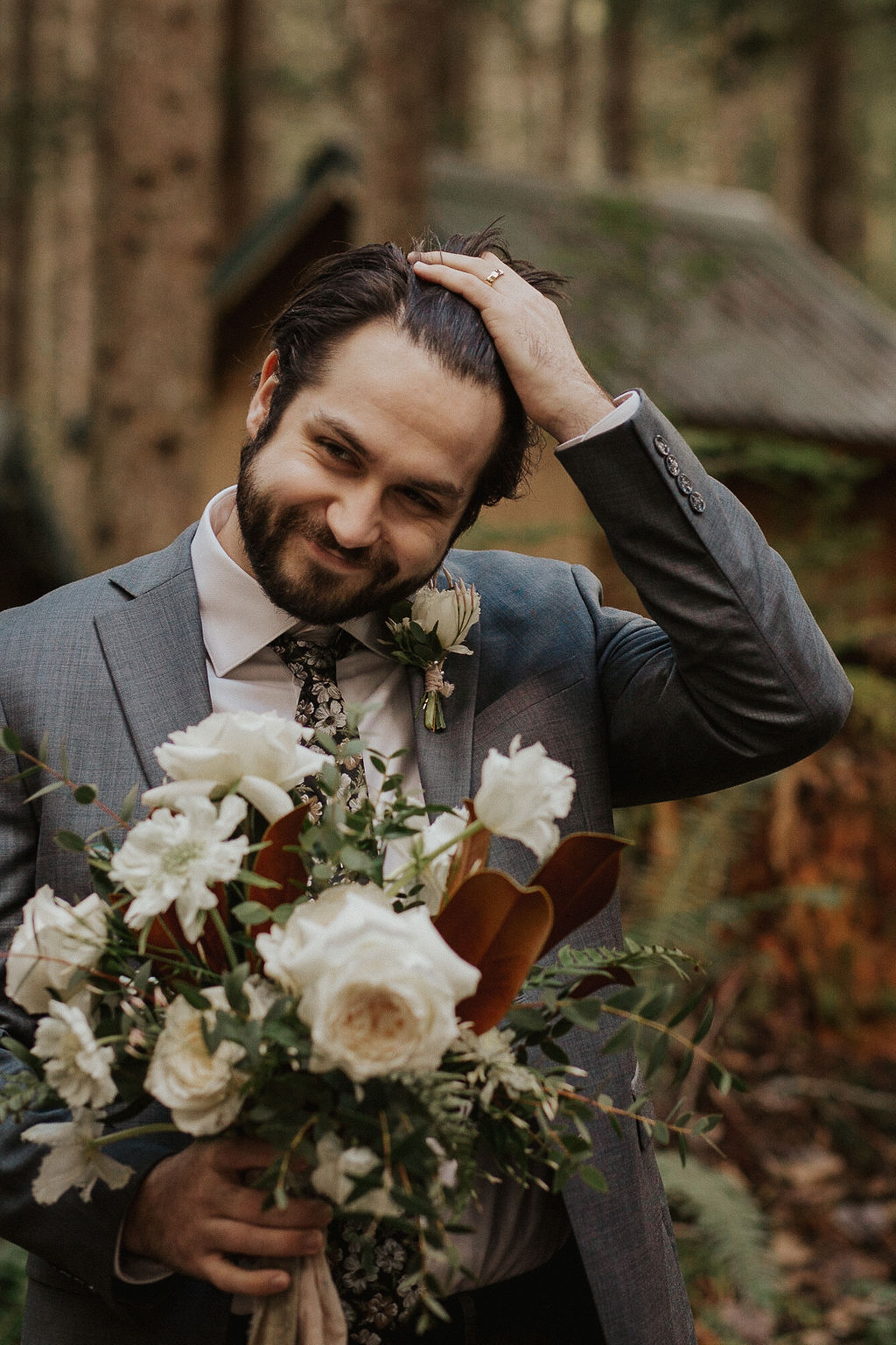 groom holding bouquet at forest elopement