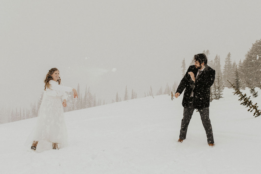 bride and groom have a snowball fight at their winter elopement