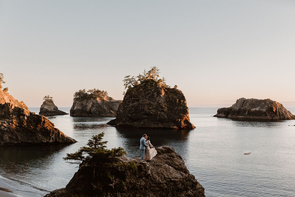 couple shares a cliffside kiss at sunset for their secret beach elopement in brookings oregon
